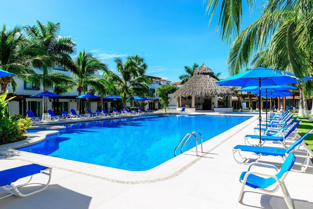 伊斯塔帕EXCLUSIVA VILLA EN LA ZONA HOTELERA DE IXTAPA_ZIHUATANEJO的一个带蓝色椅子和遮阳伞的游泳池
