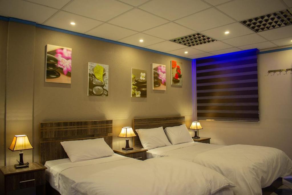卡特勒博尔纳Hotel Styled Apartment in Heart of Quatre Bornes的两张位于房间的床,配有两盏灯和墙上的照片