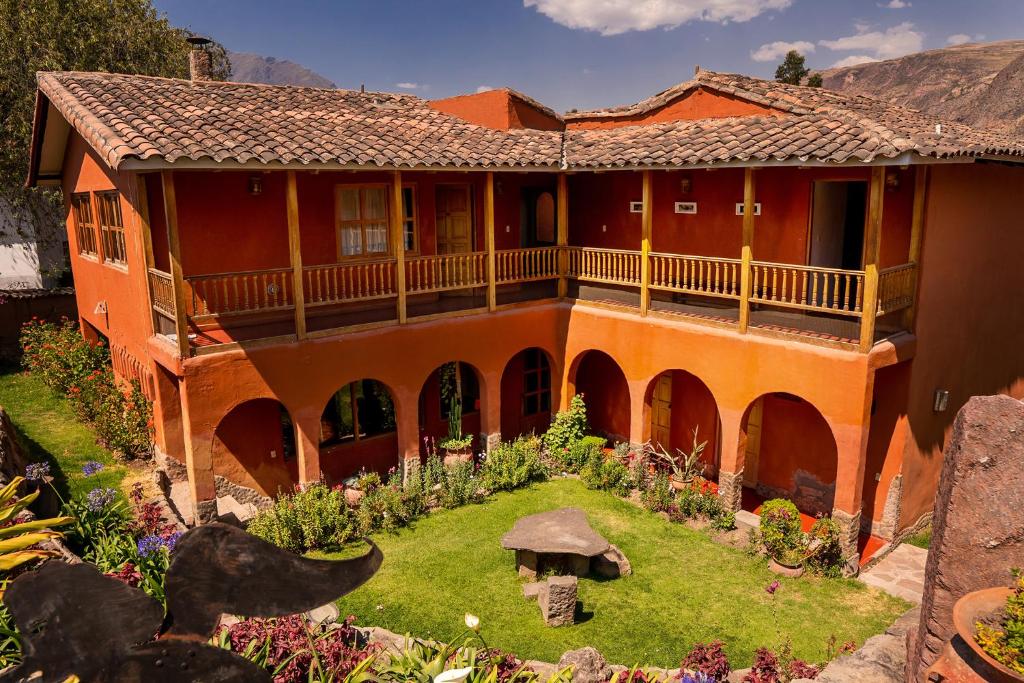 乌鲁班巴Luna Rumi Hotel-Lodge Urubamba的一座橙色的房子,前面有一个花园