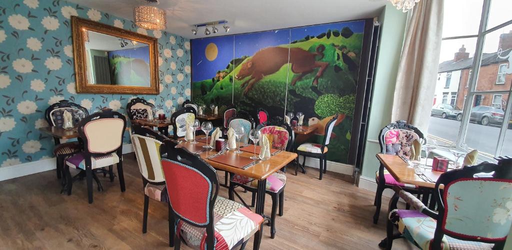 林肯The Bronze Pig的餐厅设有桌椅,墙上挂有绘画作品