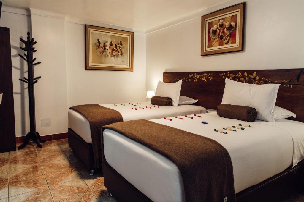 马丘比丘Hotel Retama Machupicchu的两张位于酒店客房的床,上面有鲜花