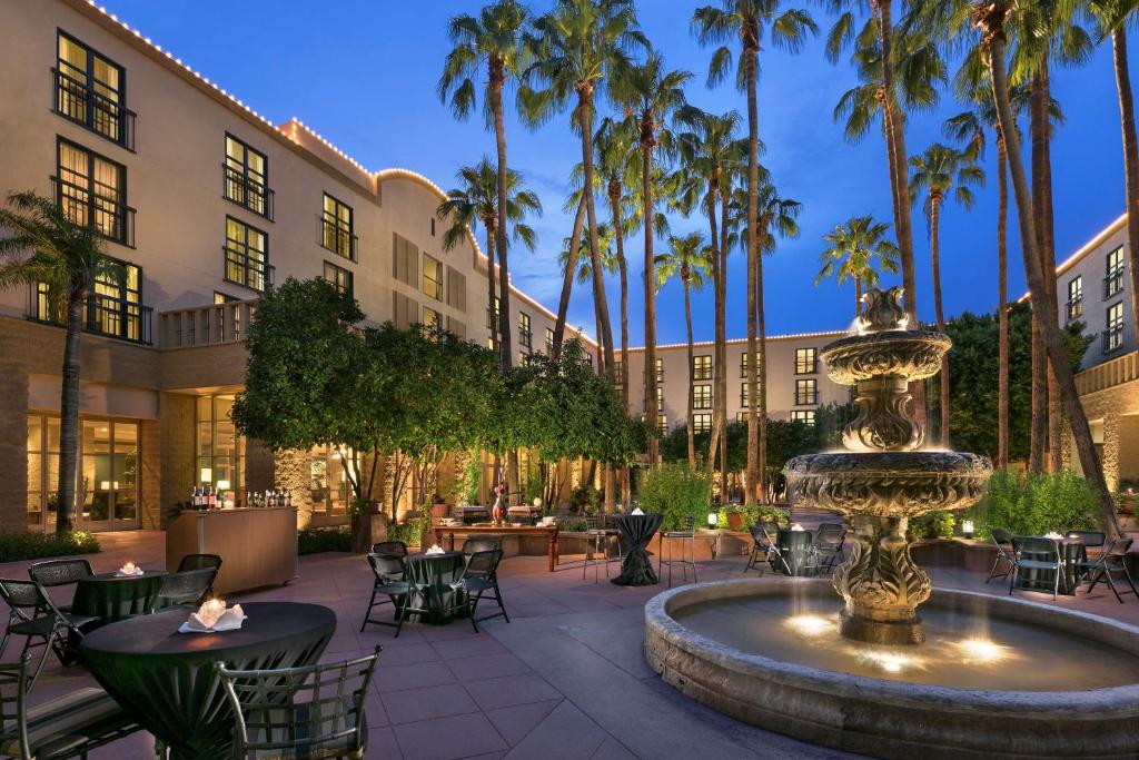 坦培Tempe Mission Palms, a Destination by Hyatt Hotel的庭院设有喷泉、桌子和棕榈树