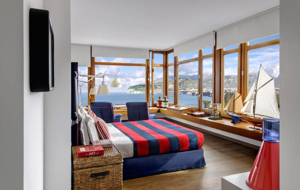 索伦托梅森米纳维塔酒店的一间卧室,配有一张床,窗户上有一艘帆船