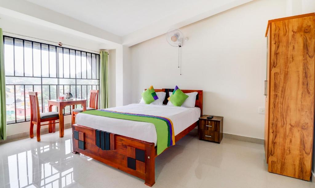 马迪凯里Treebo Trend New Redfern - Madikeri的一间卧室配有一张大床和一张桌子