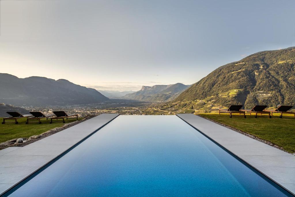 梅拉诺Arua Private Spa Villas的一座带椅子和山脉背景的无边泳池