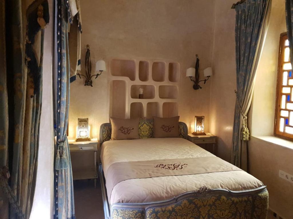 拉腊什Sultana larache的一间卧室设有床、两张桌子和一扇窗户