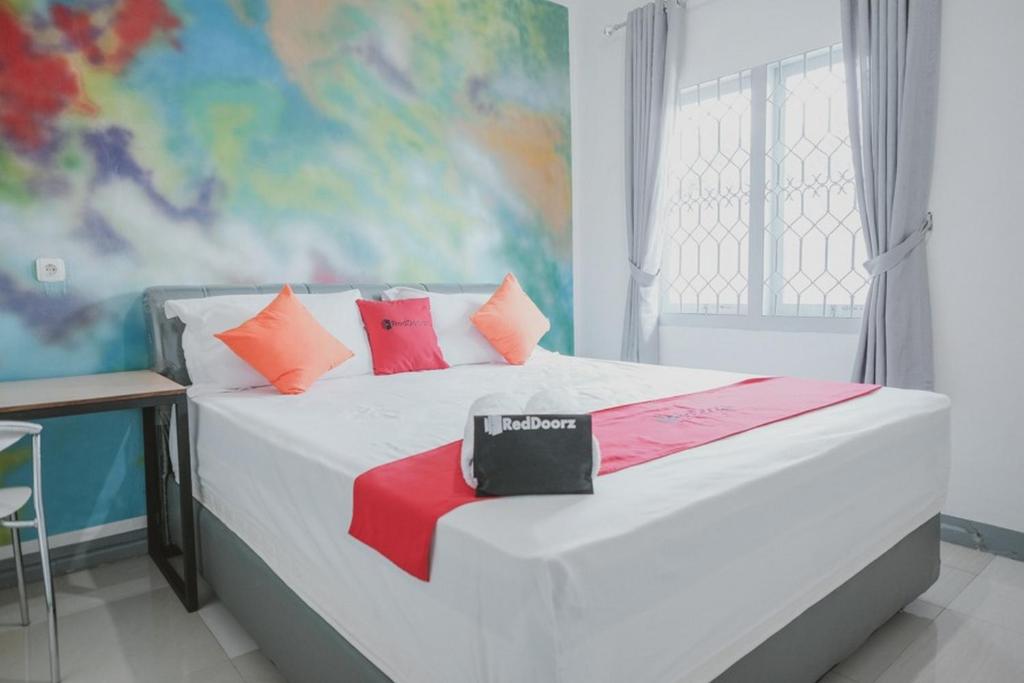 PaalmerahRedDoorz @ Beringin Jambi的卧室配有白色的床和色彩缤纷的枕头
