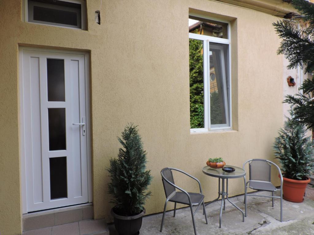 奥拉迪亚Old Town Apartament Oradea的庭院配有两把椅子和一张桌子,并设有两扇窗户。