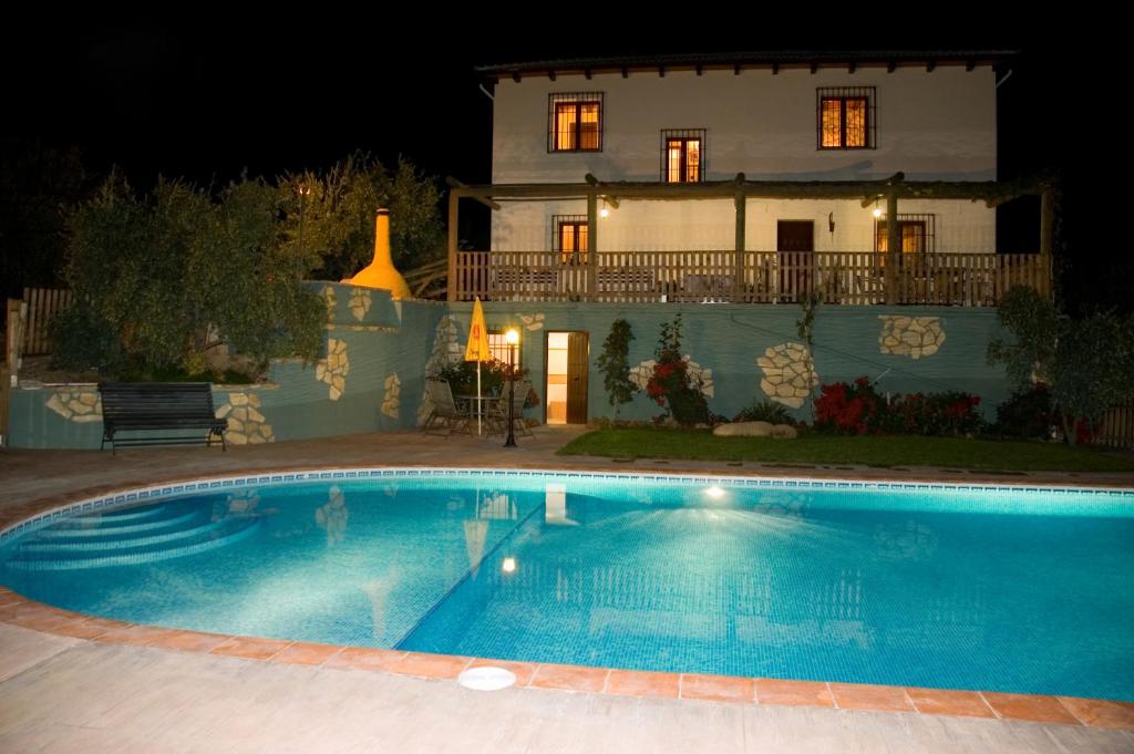 CarcabueyCasa Rural El Tejar Viejo的夜间在房子前面的游泳池