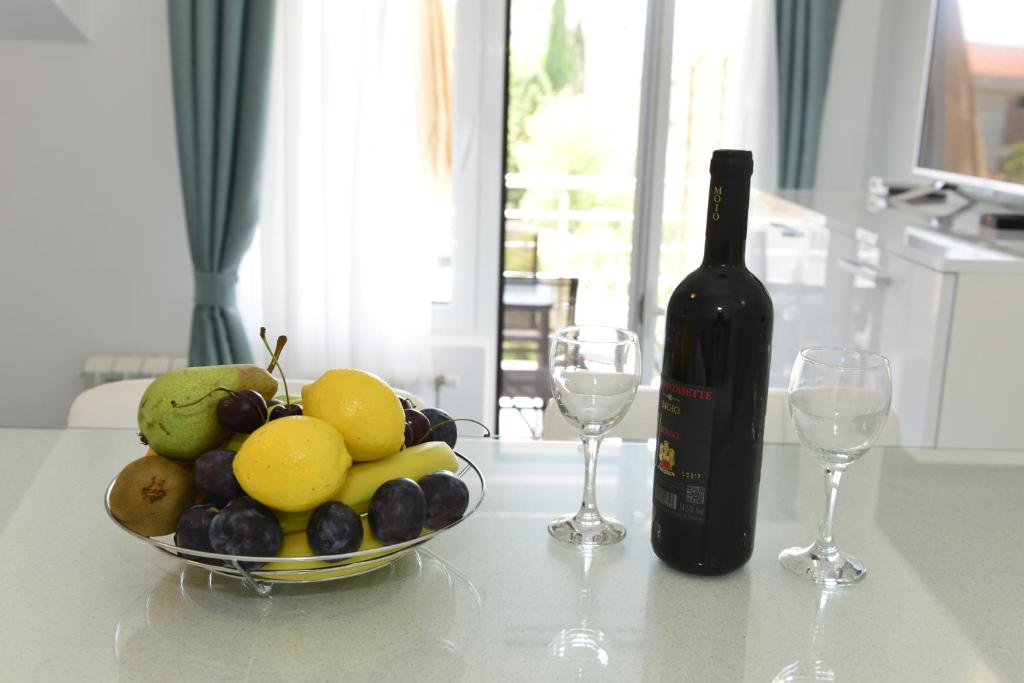 蒂瓦特Apartmani Stefanija的一瓶葡萄酒和一碗水果放在桌子上