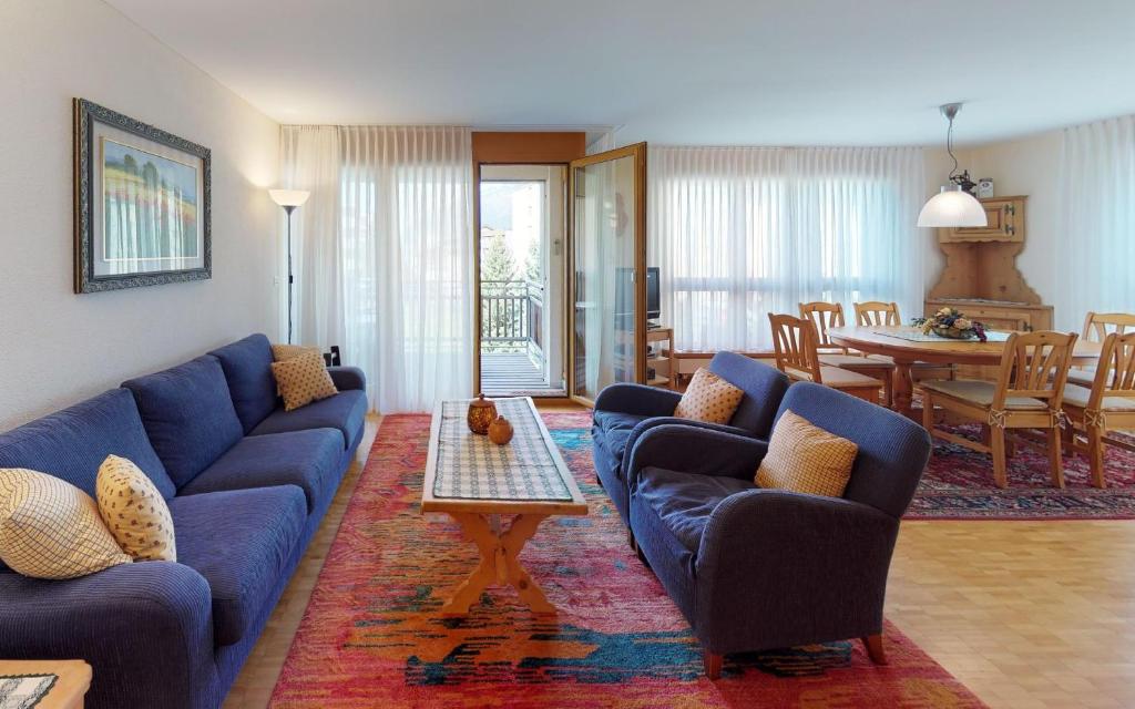 圣莫里茨Surpunt 44的一间带蓝色沙发的客厅和一间用餐室