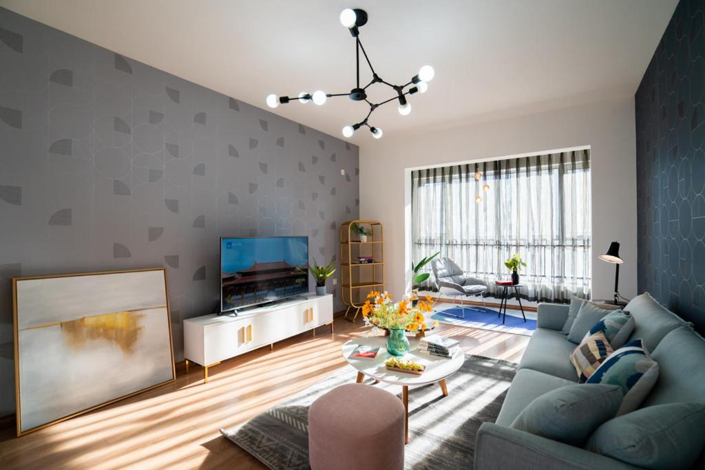 哈尔滨【路客】哈尔滨市南岗区·哈西万达·路客精品公寓·00182520的客厅配有蓝色的沙发和电视