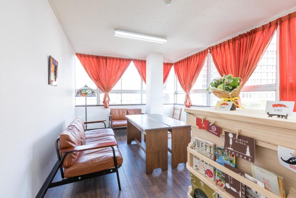 长崎Almas Guest House(アルマス）的客厅配有红色窗帘和桌椅