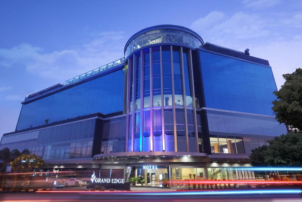 三宝垄Grand Edge Hotel Semarang - CHSE Certified的一座大型玻璃建筑,上面有蓝色的灯光