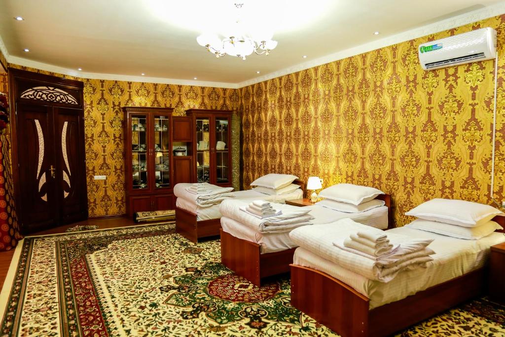 布哈拉Murod Yusufiy Boutique Hotel的一间设有四张床和地毯的房间