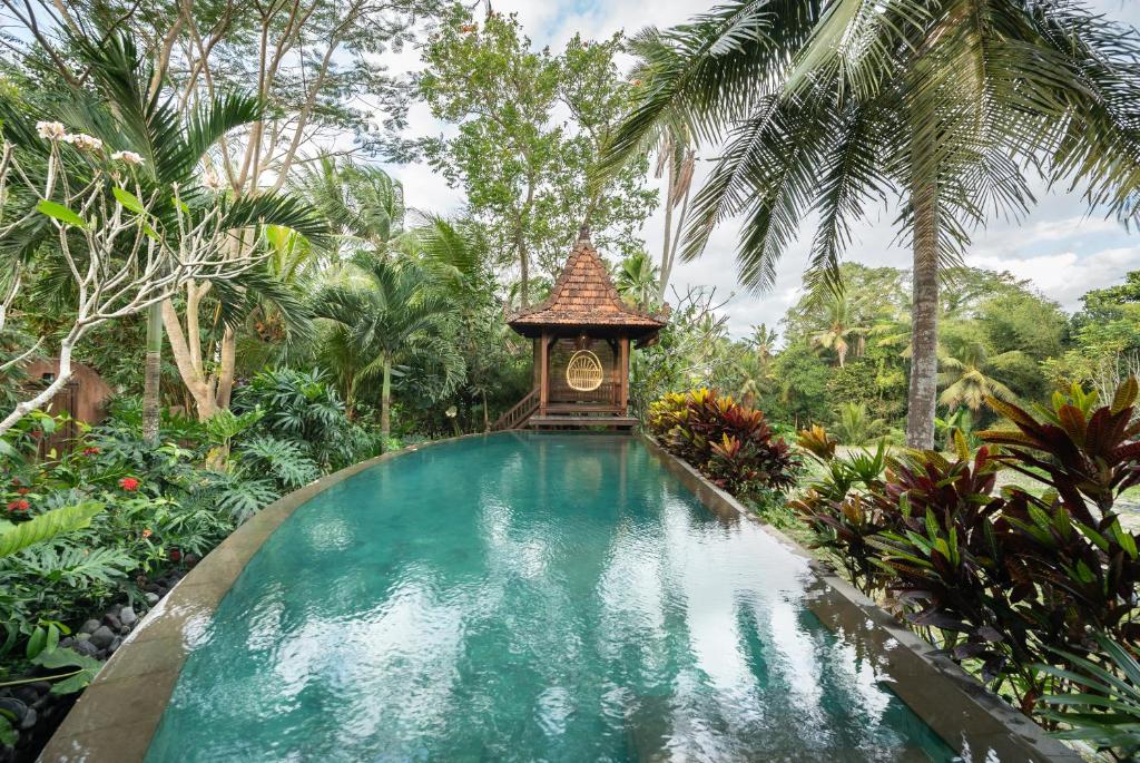 乌布Villa Uma Anyar- Joglo Uma的花园中的游泳池,里面装有钟