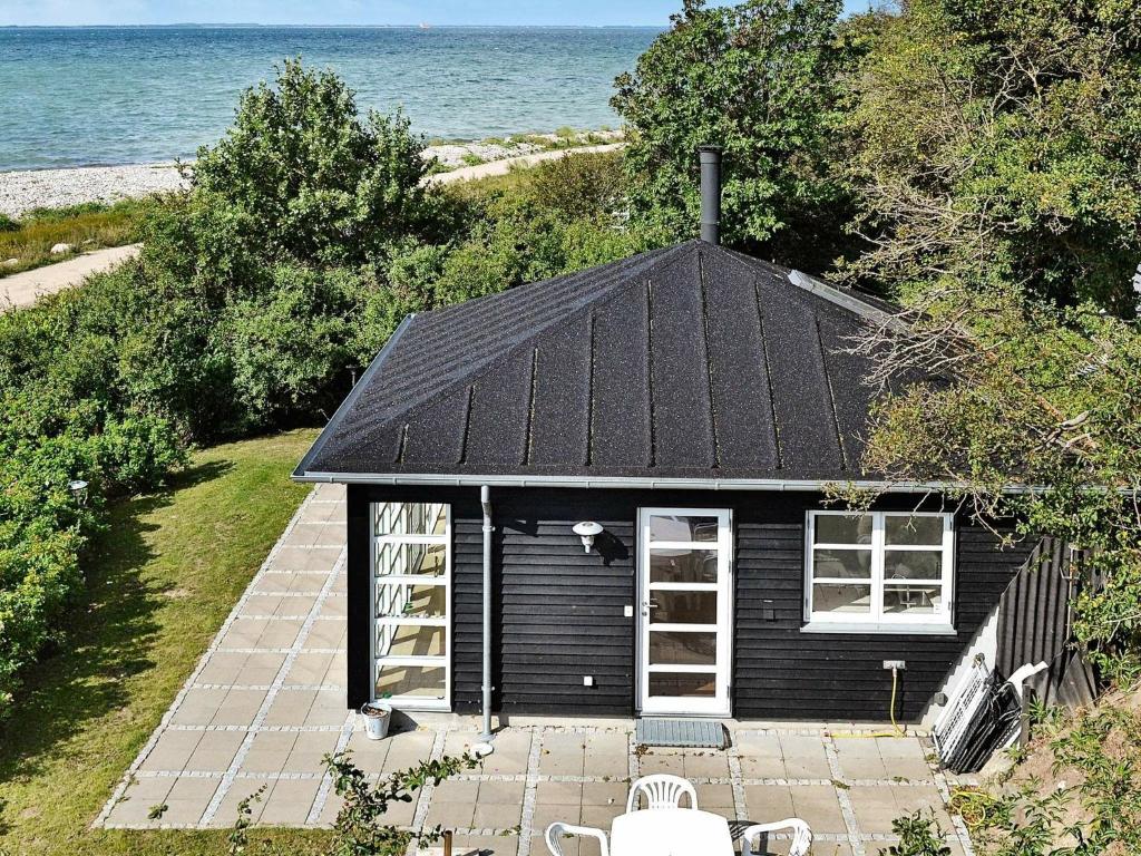 Martofte4 person holiday home in Martofte的一座黑色屋顶和海洋的小房子