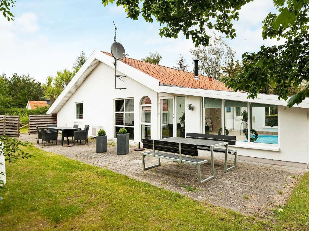 埃贝尔托夫特8 person holiday home in Ebeltoft的白色的房子,配有野餐桌和长凳