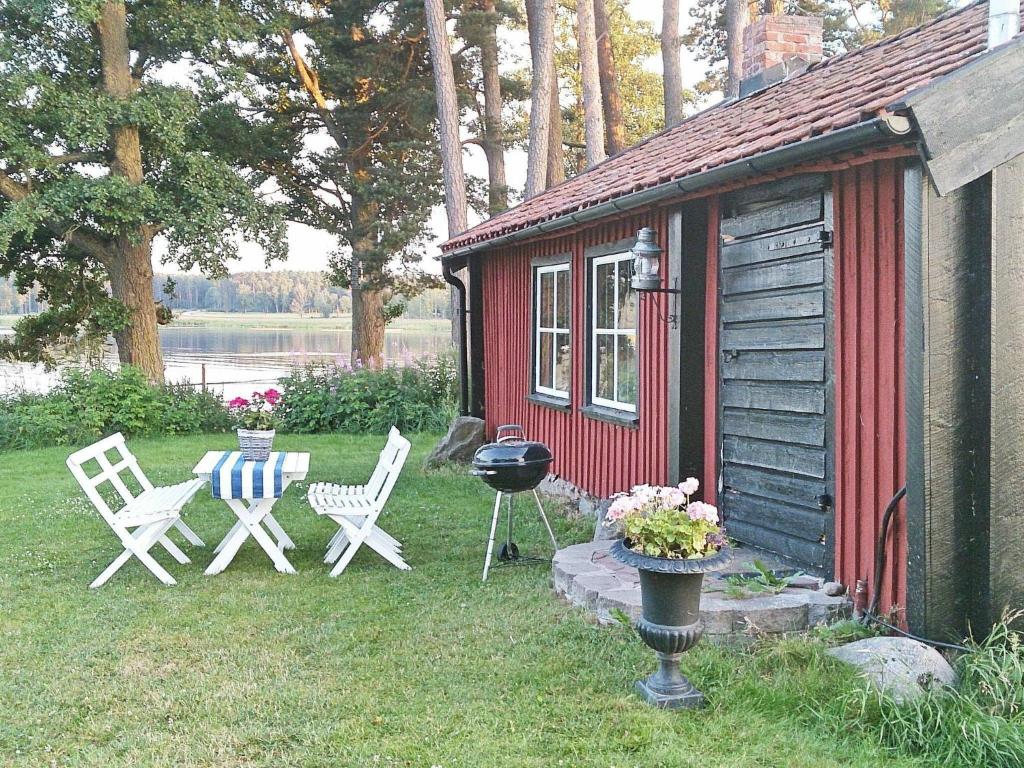 Hova4 person holiday home in HOVA的院子里的红色小屋,配有椅子和烧烤架