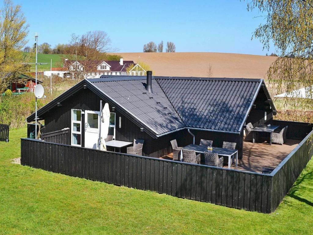 Brunshuse6 person holiday home in Haarby的一座黑屋顶的房子和一个带椅子的甲板