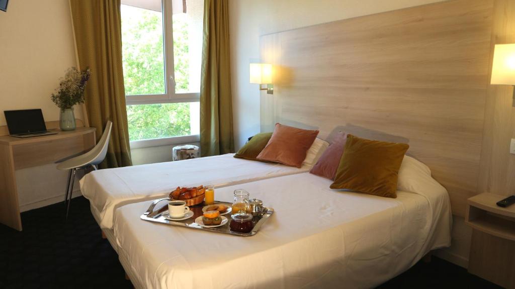 图卢兹奥赛酒店的一间酒店客房,床上放着一盘食物