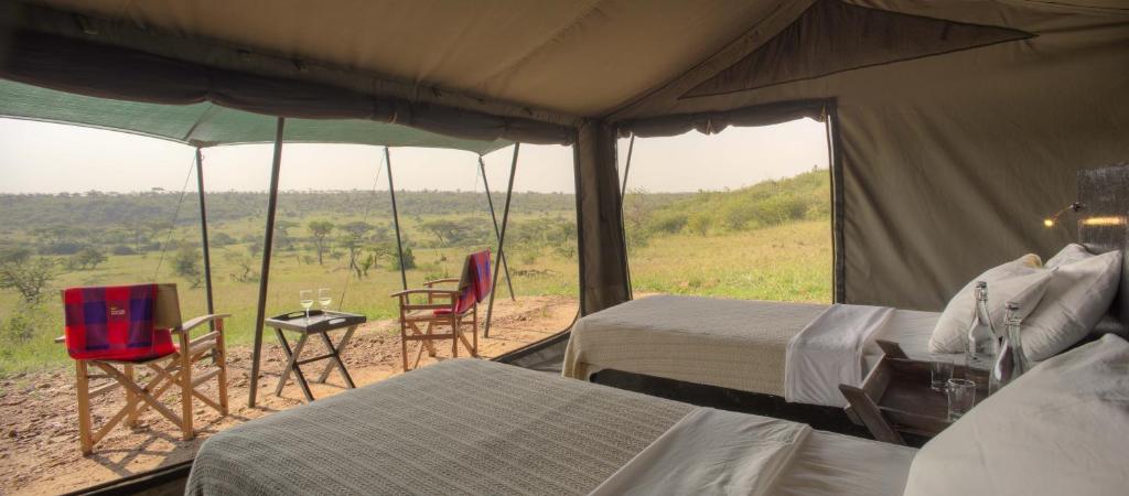 NaboishoBasecamp Wilderness的帐篷配有两张床和一张桌子及椅子