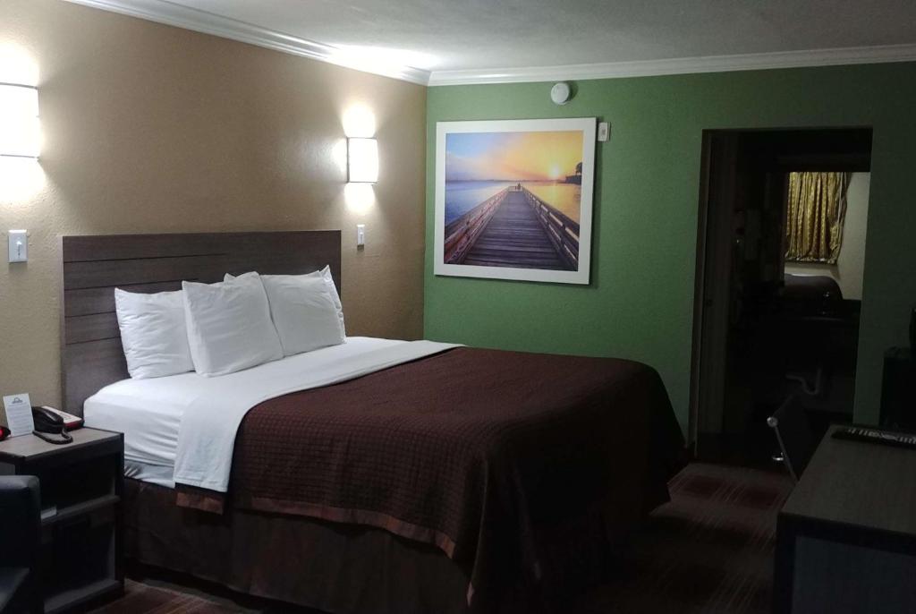 休斯顿休斯顿戴斯酒店的酒店客房设有一张床,墙上挂有绘画作品