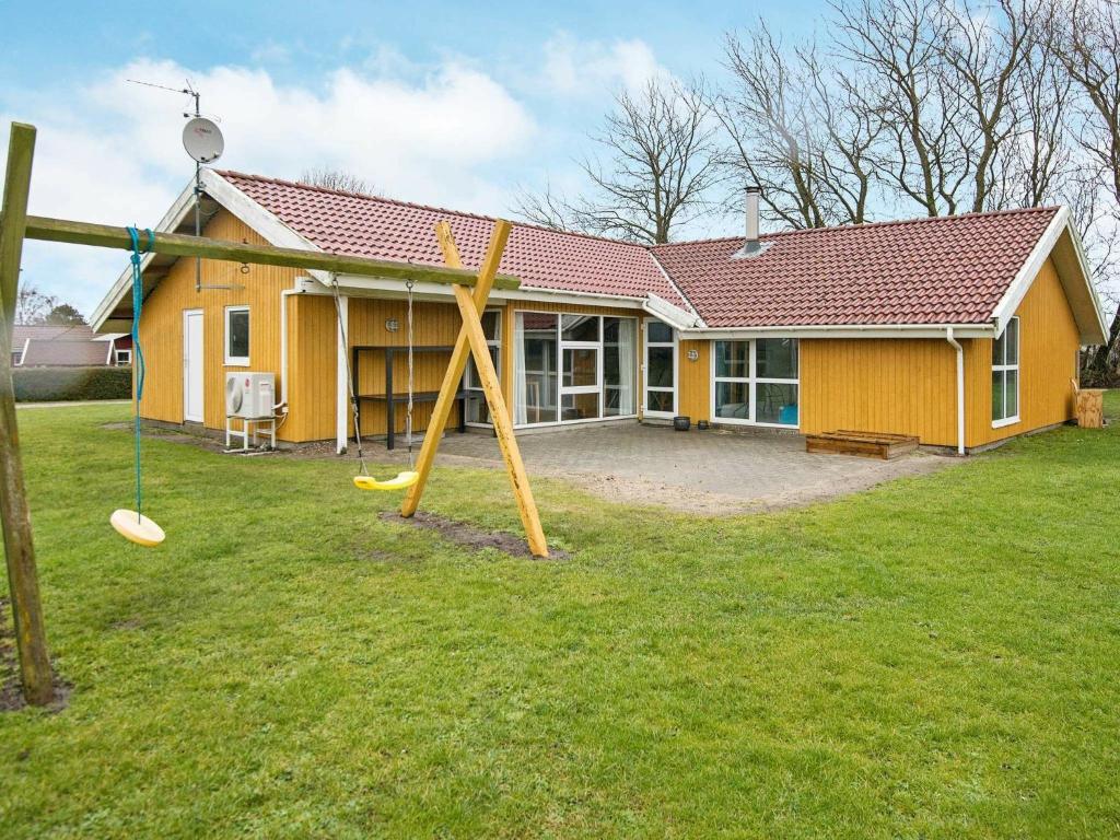 诺德堡12 person holiday home in Nordborg的庭院内带游乐场的黄色房子