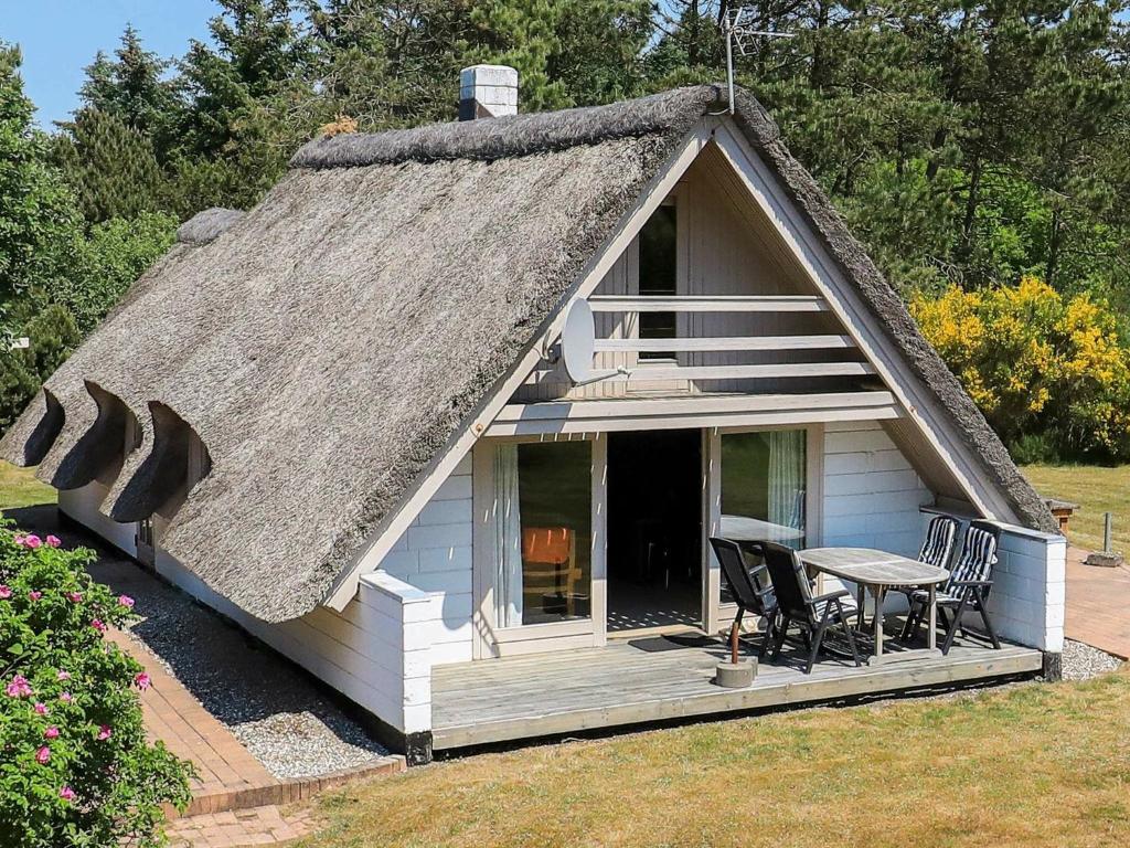 NørbyHoliday Home Fyrrealle的小屋设有茅草屋顶、桌子和椅子