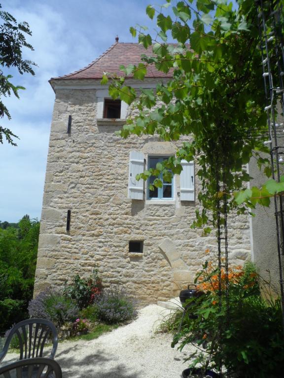 CarluxLa Petite Tour的一座石头建筑,设有两扇窗户和长凳