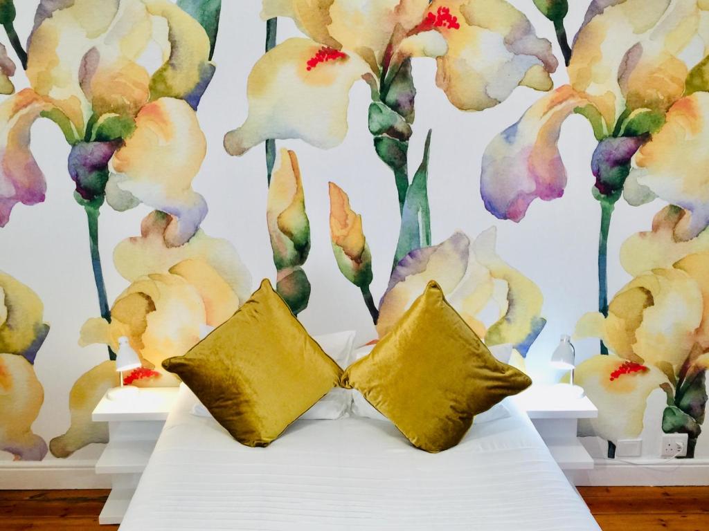 开普敦Mediterranean Villa Guesthouse的花卉墙前的一张带两个枕头的床