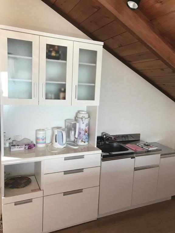富士市F.stic＿house的厨房配有白色橱柜和炉灶。