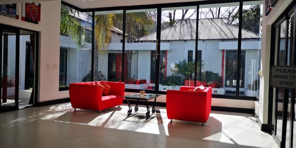 约翰内斯堡21翠鸟旅馆的客厅配有2把红色椅子和桌子