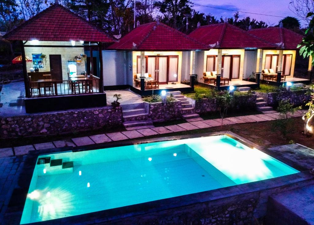 珀尼达岛Kampuak Cottages的夜间在房子前面的游泳池