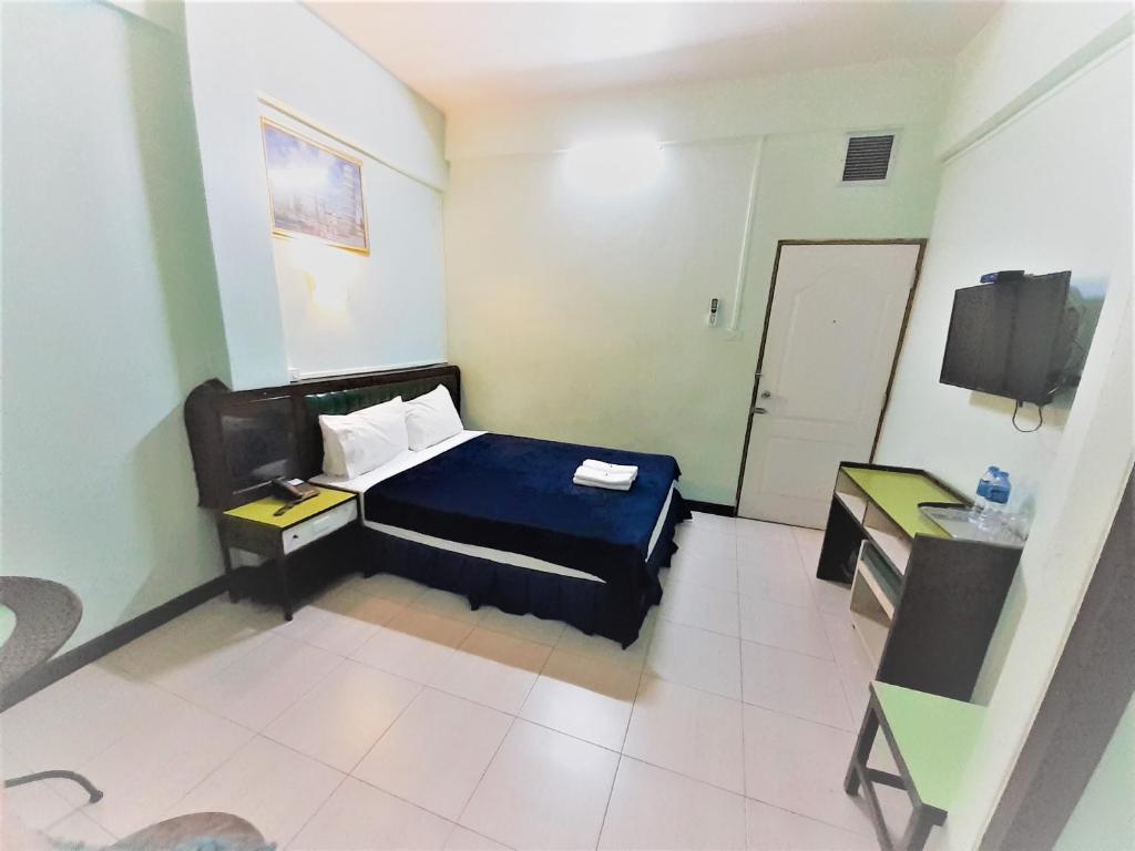 合艾新加坡酒店的一间卧室配有一张床、一张书桌和一台电视