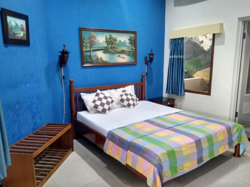 玛琅艾尼之家旅馆的一间卧室设有一张床和蓝色的墙壁