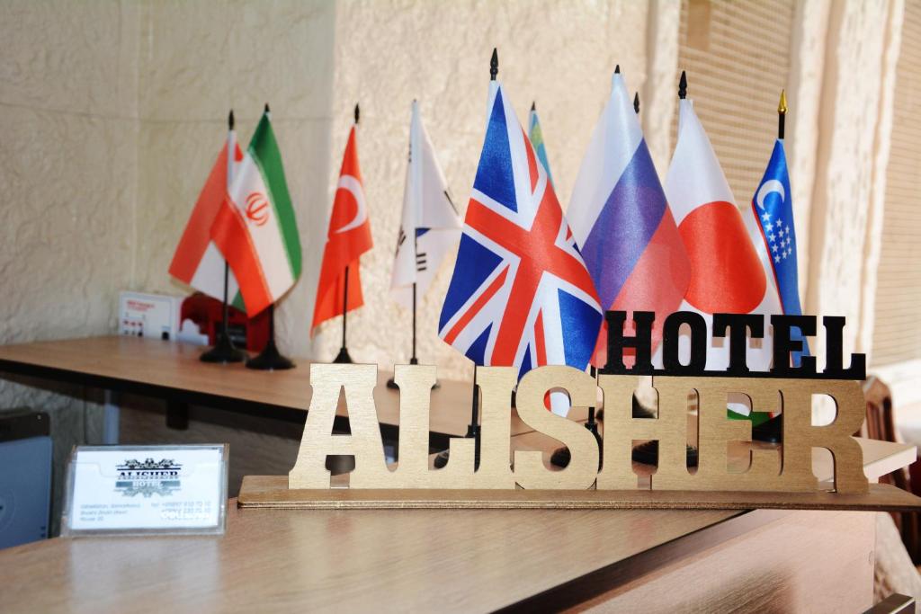 撒马尔罕Alisher B&B Hotel的桌子顶部带有旗帜的木标志
