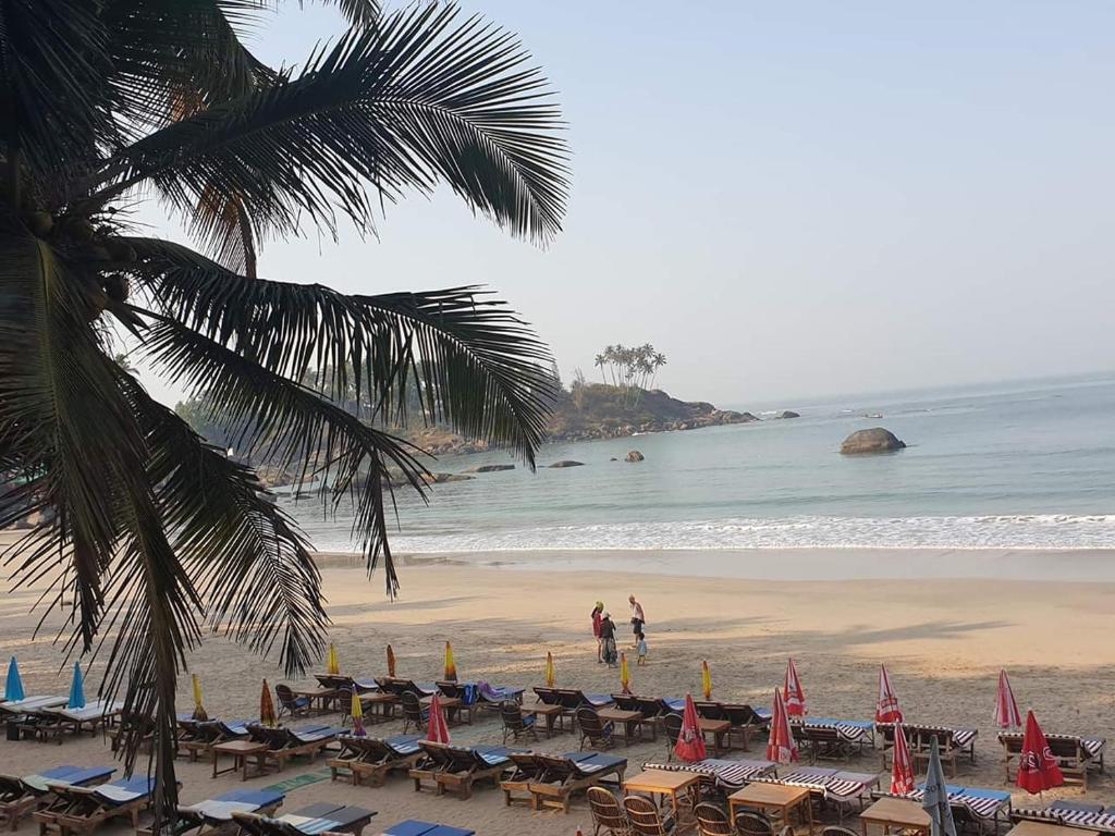 AguadaAlexmarie Guest house 5 min to candolim Beach的海滩上设有椅子和遮阳伞,还有大海