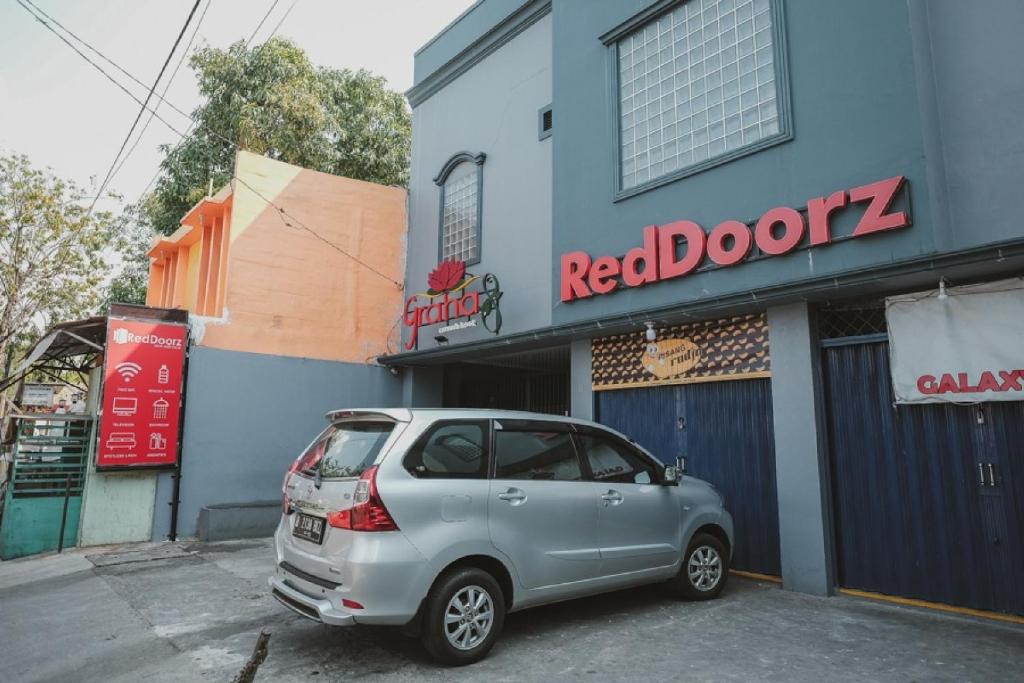 雅加达RedDoorz near RSUD Koja的停在大楼前的银色汽车