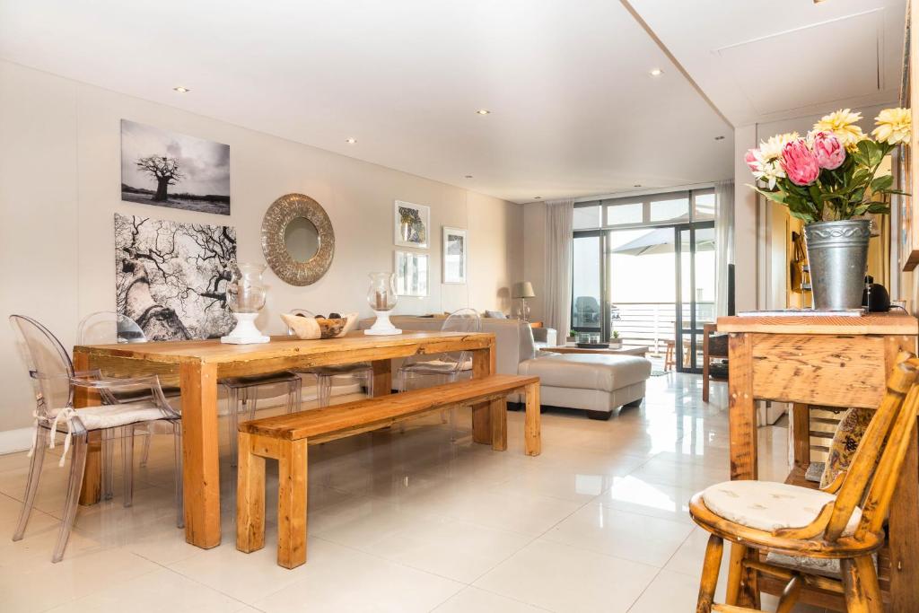 比格湾Luxury Ocean View 2 Bed Apartment 259 Eden on the Bay, Blouberg, Cape Town的客厅配有木桌和椅子