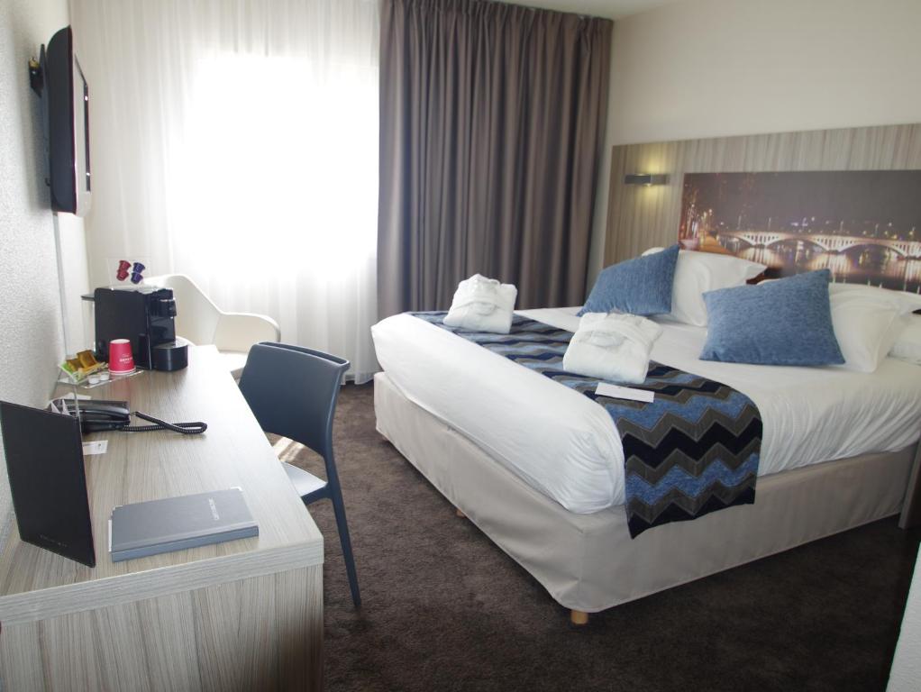 里昂Hôtel Saphir Lyon的酒店客房设有一张大床和一张书桌。