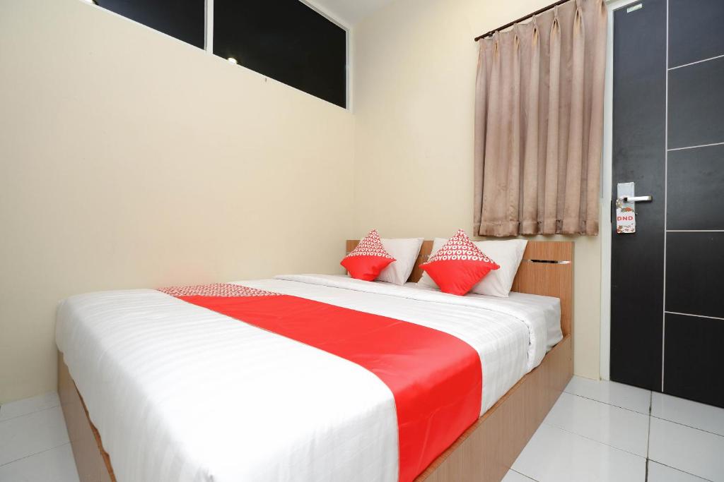 三宝垄Super OYO 1250 Unta Residence的一间卧室配有红色和白色枕头的床