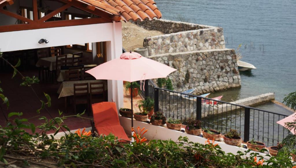 San Antonio Palopó阿提兰别墅旅馆的一把粉红色的伞,坐在大楼的阳台上