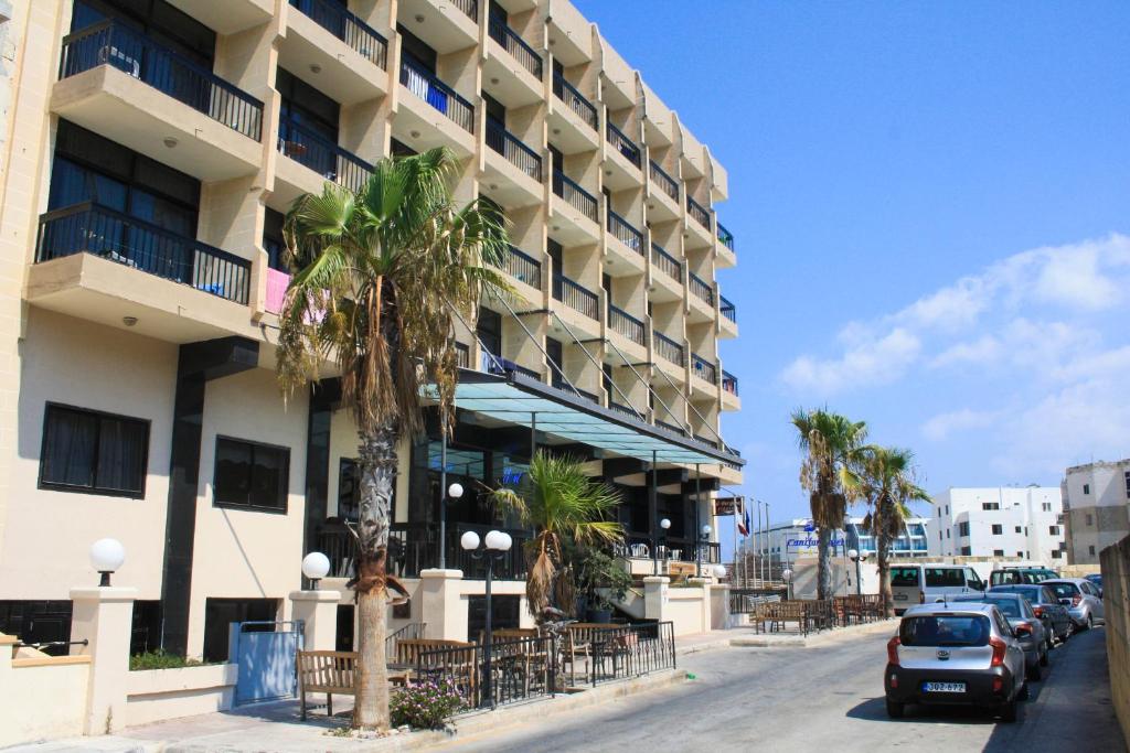 圣保罗湾城卡尼富尔酒店的街道前方有棕榈树的建筑