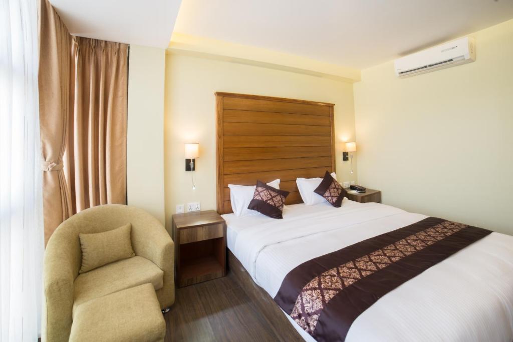 加德满都Ganapati Airport Hotel的配有一张床和一把椅子的酒店客房