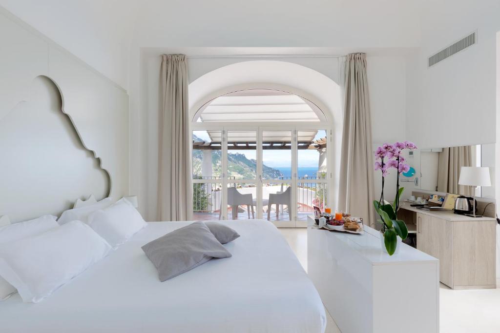 拉维罗皮耶迪蒙特别墅酒店的一间白色的卧室,配有一张床,享有海景