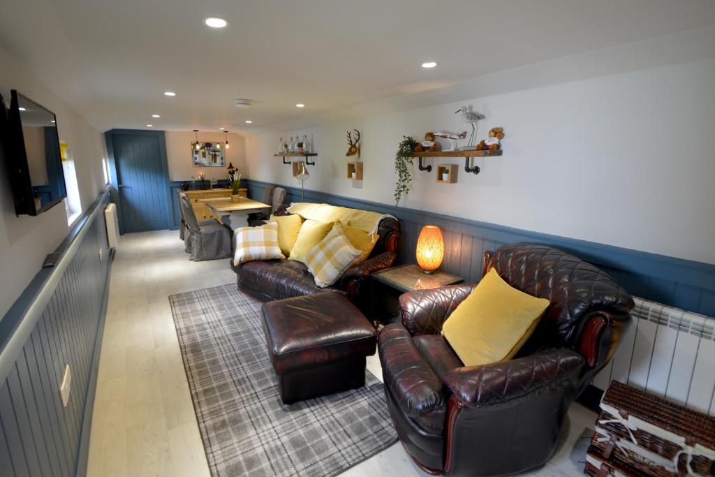 爱丁堡Craiglockhart Lodge的客厅配有皮革家具和电视