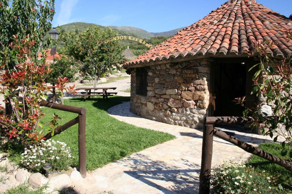 赫尔特Complejo Rural Los Chozos Valle del Jerte的花园内带长凳的小石头建筑