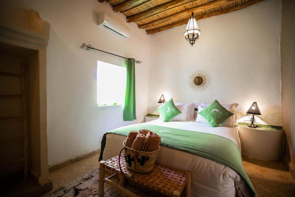梅尔祖卡Riad Kasbah Aiour的一间卧室配有一张带绿色床单的床和一扇窗户。
