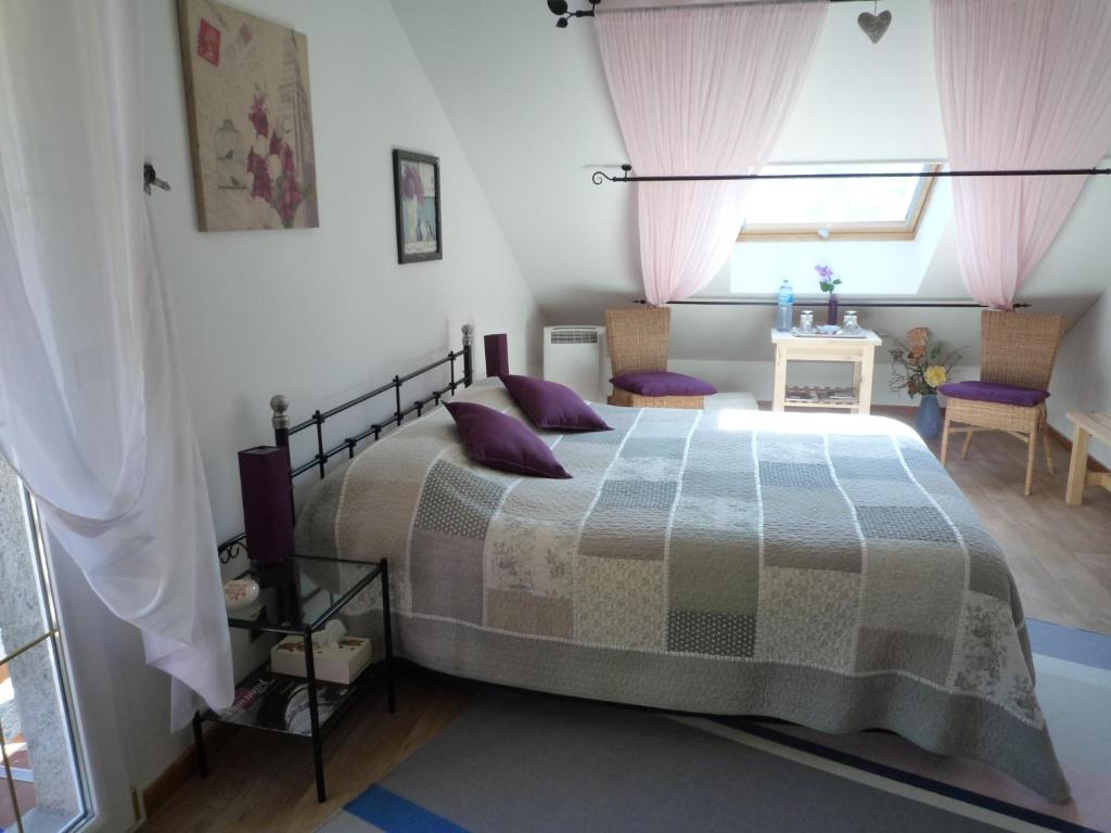 博讷Le Verger du Sausset的一间卧室配有一张带紫色枕头的床和窗户。